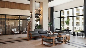 Un vestíbulo amplio con un sofá, sillas, una mesa de centro y un ventanal que ofrece vistas del exterior del edificio.