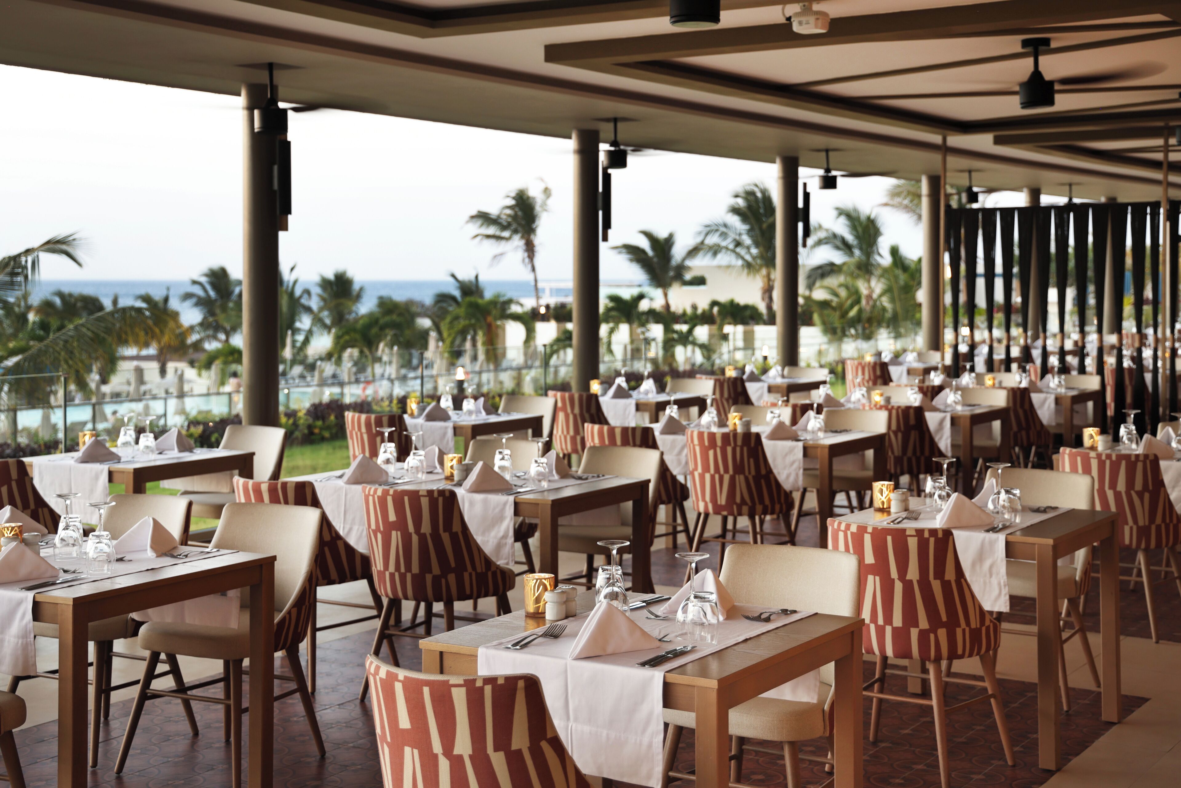 Un restaurante con mesas dispuestas para comer, terraza al aire libre y vista al océano.