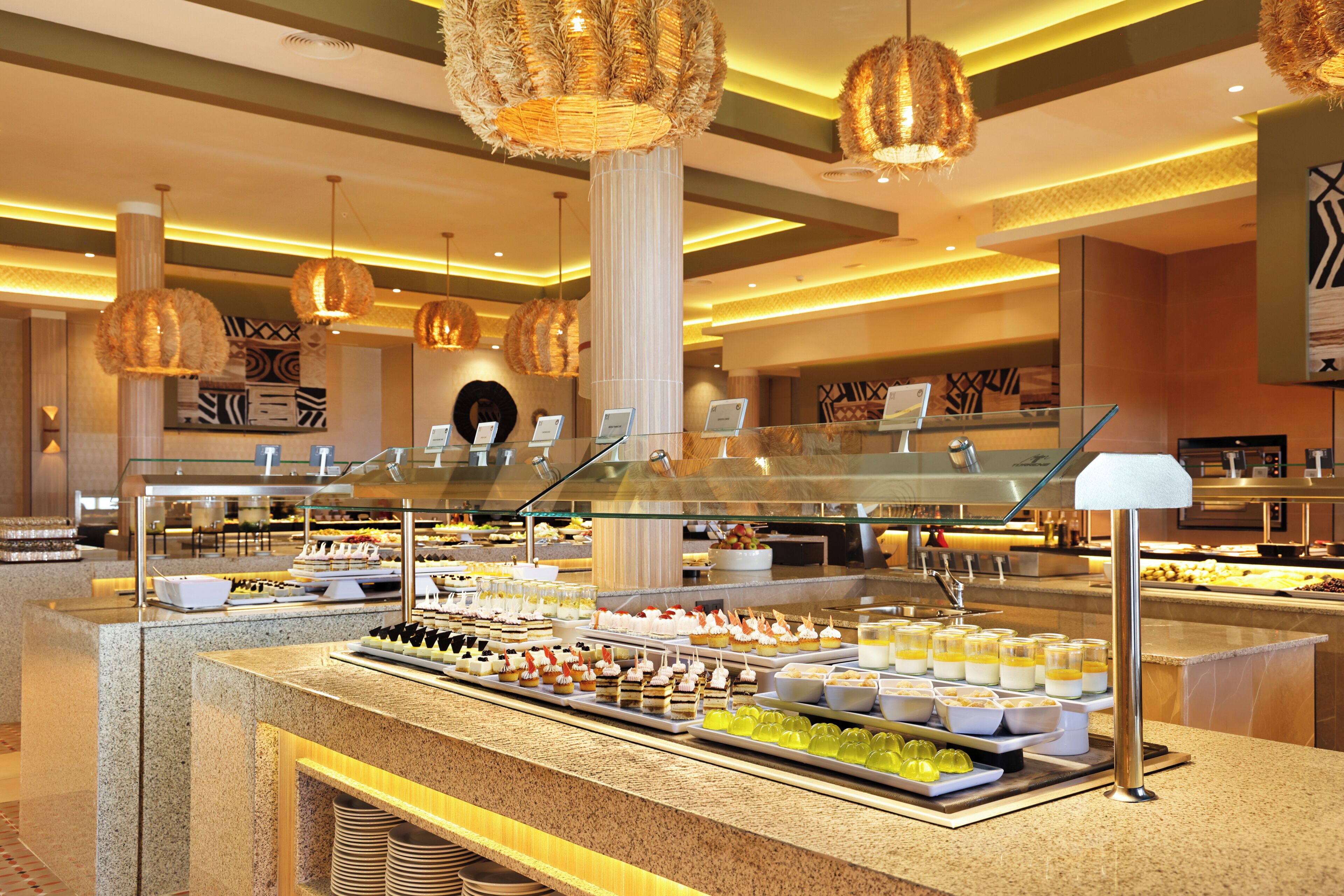 A buffet with various food items, a glass display case, and decorative hanging lights.