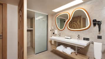 A modern bathroom with a glass shower enclosure, a vanity with a mirror, and a towel rack.