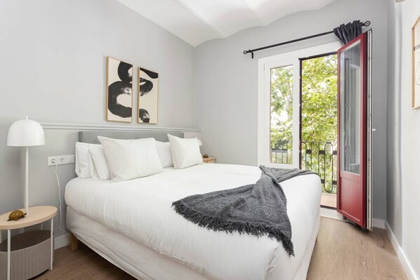 Un dormitorio con una cama grande, una mesita de noche, una lámpara y vistas al exterior a través de una puerta corredera.