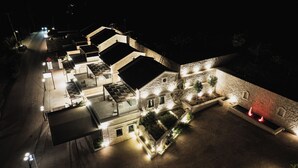 Een meerhoog hotel met buiten zitgedeeltes, een gevel van natuursteen en een goed verlichte ingang.