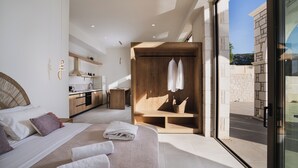 Een moderne slaapkamer met een groot bed, een houten garderobe, een kitchenette en uitzicht op buiten.