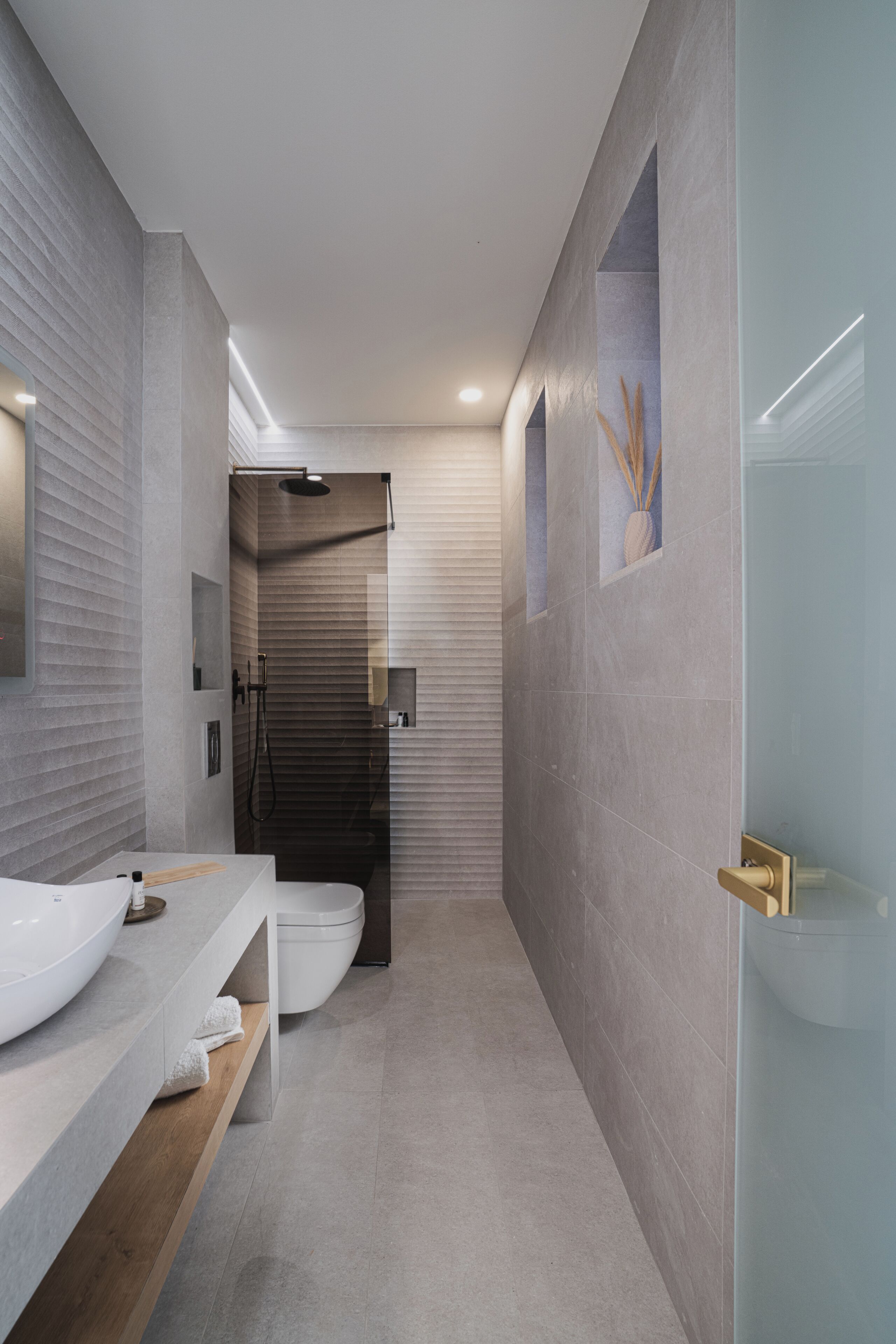 A modern bathroom with a large sink, a shower, and a toilet.
