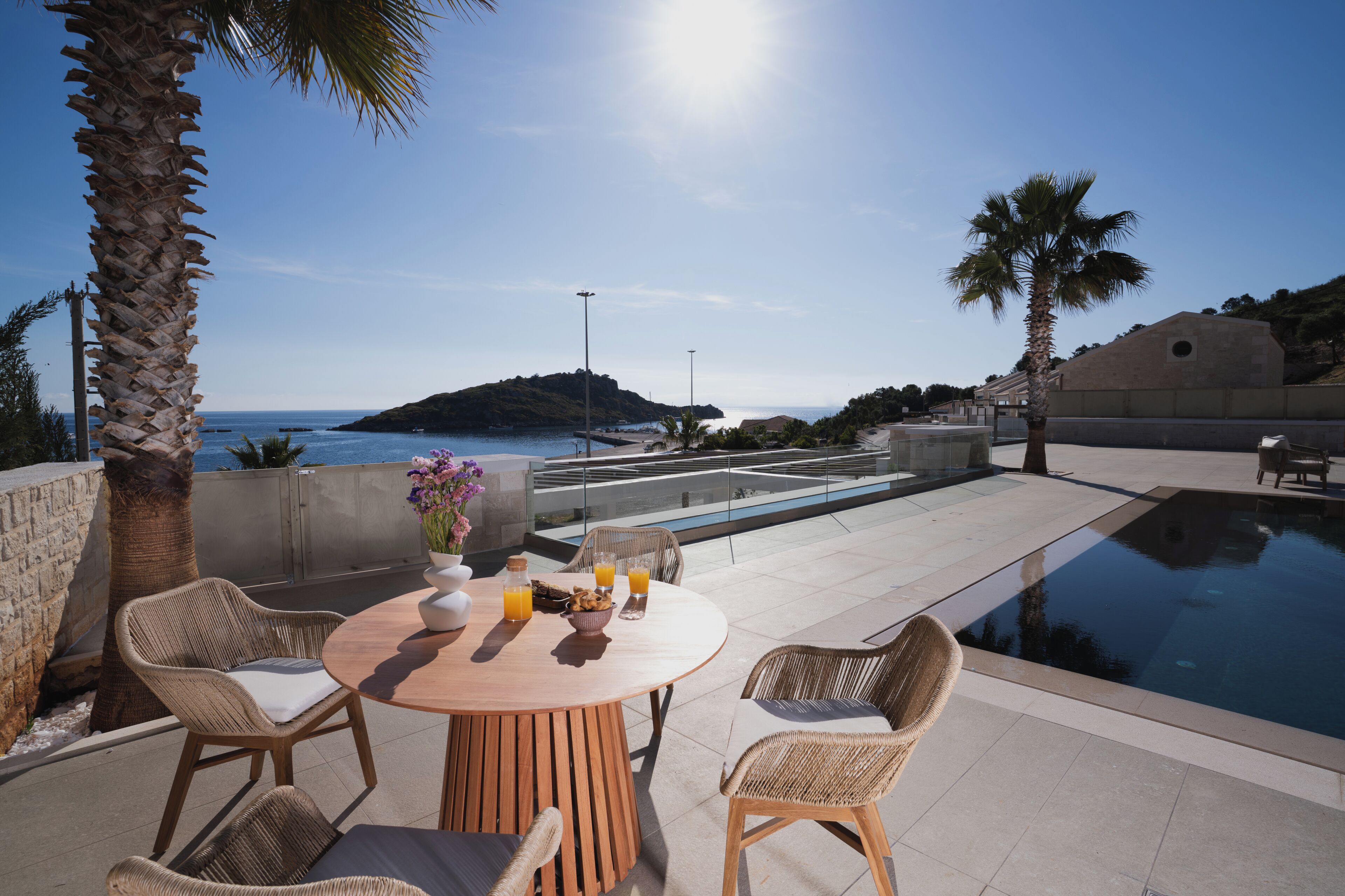 Terraza en la azotea con piscina, mobiliario de mimbre y vistas al mar.