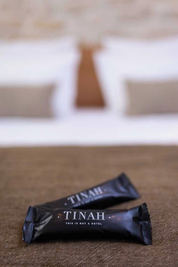 Zwei schwarze Pakete mit dem Aufdruck "TINAH" auf einer strukturierten Oberfläche, unscharfer Hintergrund.