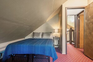 Un dormitorio con cama, mesita de noche, lámpara y suelo cubierto de alfombra roja.