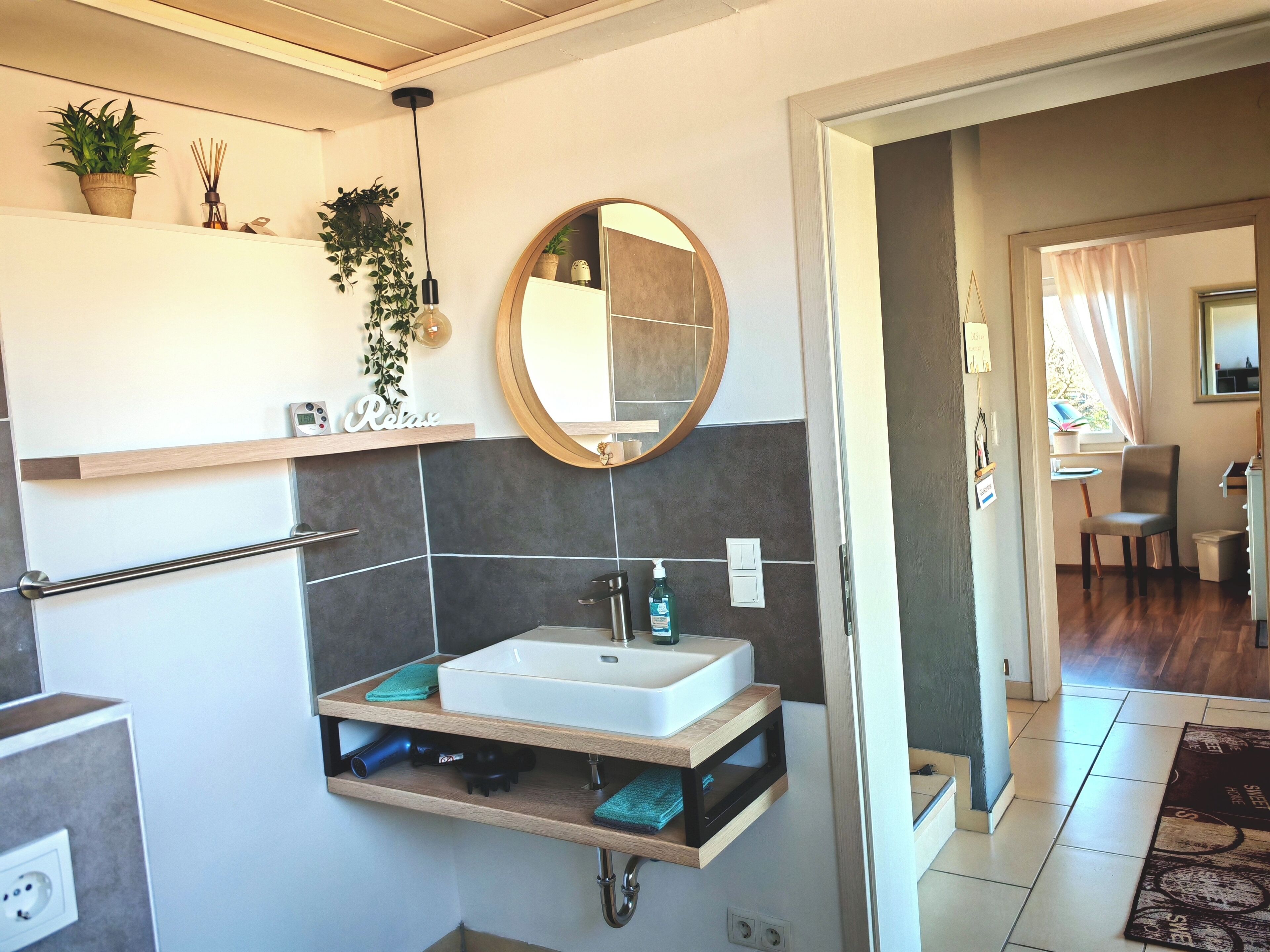 Un baño moderno con lavamanos integrado, un espejo y un perchero para toallas.