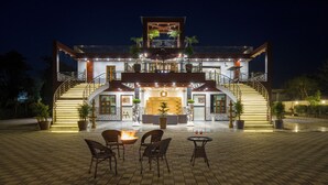 Un hotel de varios pisos con una entrada imponente, zona de estar al aire libre y una chimenea decorativa.