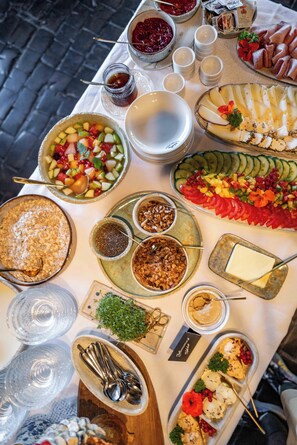 Une table garnie de divers aliments et ustensiles, notamment un plateau de fruits, une planche de fromages et plusieurs bols contenant des condiments.