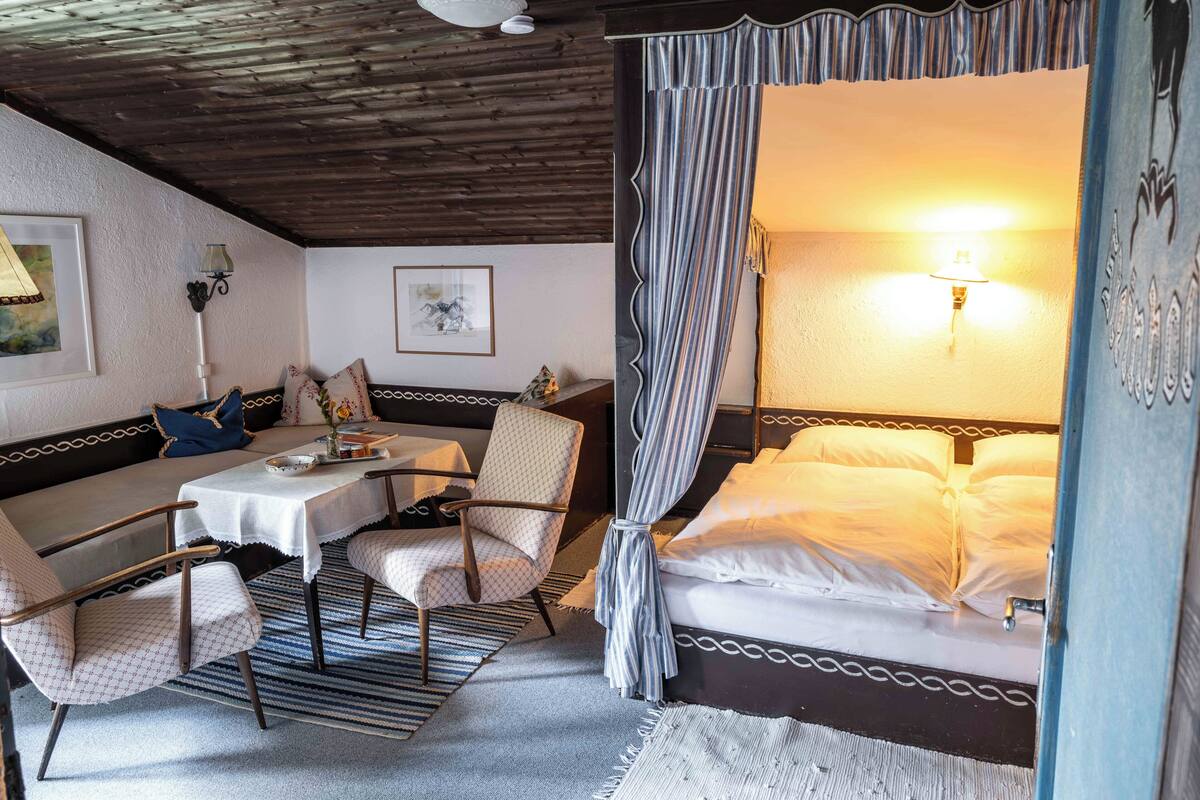 A cozy room with a bed, a sofa, a table, and two chairs.