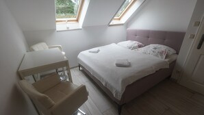 A bedroom with a bed, a desk, and a chair. There are two windows providing natural light. - Ferienwohnung Erika · Nature & Peace in Lausitz · 3 Rooms, 8 Guests (Neiße-Malxetal)