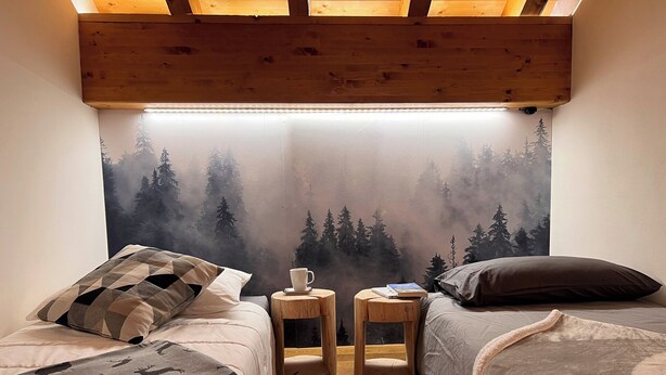 A cozy bedroom with two beds, a large window with a forest view, and a wooden ceiling. - Beautiful accommodation near Bormio (Valdidentro)