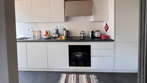 A modern kitchen with white cabinets, a black countertop, and a wooden ceiling. - Beautiful accommodation near Bormio (Valdidentro)