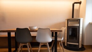 A dining area with a wooden table, two chairs, and a modern stove. - Beautiful accommodation near Bormio (Valdidentro)