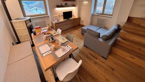A cozy living space with a wooden dining table, a grey sofa, and a TV on a wooden cabinet. - Beautiful accommodation near Bormio (Valdidentro)