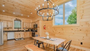 A wooden cabin interior with a kitchen, dining area, and large windows. - 🐻 Bear Crossing🌲 Secluded Views, Hot Tub & Game Room (Gatlinburg)
