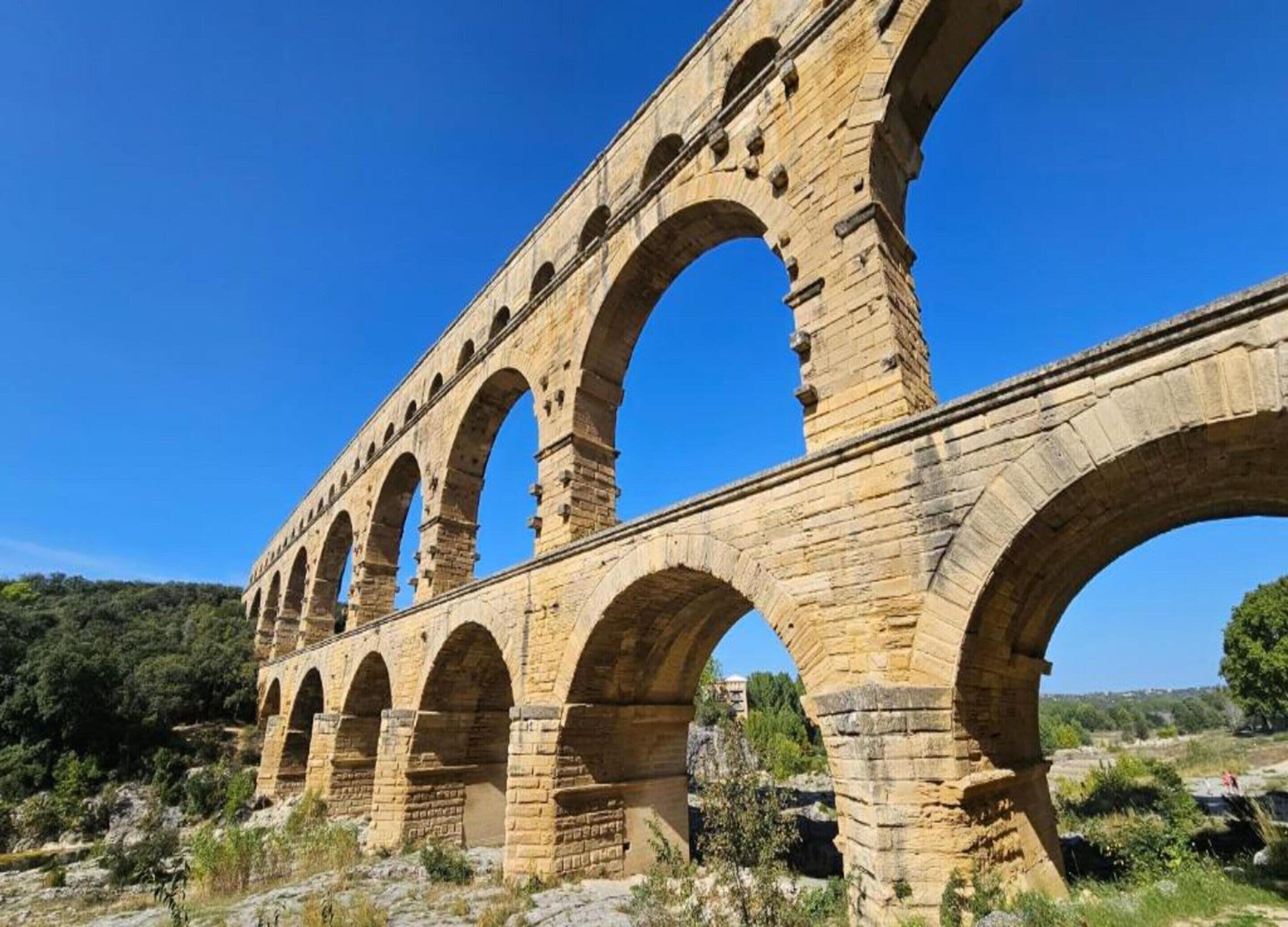 A stone aqueduct with multiple arches, set against a clear blue sky.