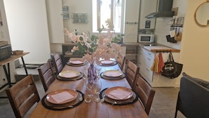 Une table à manger dressée pour six personnes, avec des assiettes, des couverts et un vase de fleurs.