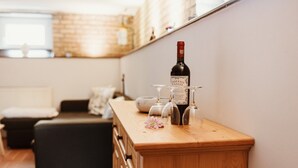 A wooden bar counter with a wine bottle and glasses, a flower, and a couch in the background. - Apartment 'Zuflucht' with Shared Terrace and Wi-Fi (Thale)