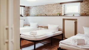 A hotel room with two beds, a brick wall, a window, and a radiator. - Apartment 'Zuflucht' with Shared Terrace and Wi-Fi (Thale)