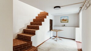 A staircase with brick steps leading to a landing, a white wall with a picture, and a small round table with a white rug. - Apartment 'Zuflucht' with Shared Terrace and Wi-Fi (Thale)