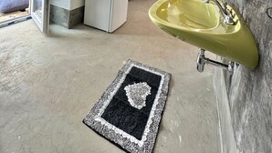 A kitchen with a white refrigerator, a yellow sink, and a black and white rug.