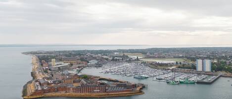 An aerial view of a coastal town with a marina, buildings, and a large body of water.