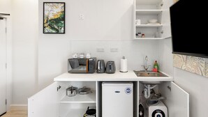 Eine kleine Küchenzeile mit Kühlschrank, Toaster, Wasserkocher und Spüle.