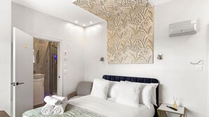 Ein Hotelzimmer mit einem Bett, einem Nachttisch, einer Wand-Klimaanlage und einem durch eine offene Tür einsehbaren Badezimmer.