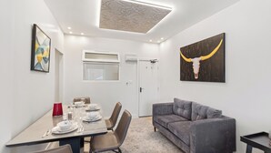 Een moderne eetruimte met een tafel voor vier personen, een grijze bank en een stierenkop kunstwerk aan de muur.