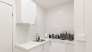 Een kleine, witte keuken met een spoelbak, een broodrooster en een magnetron.
