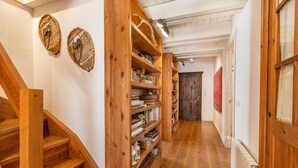 Una scala in legno conduce a un pianerottolo con scaffali e un termosifone.