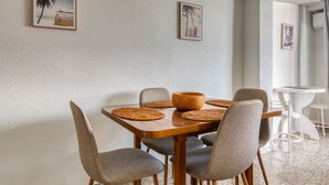 A dining area with a wooden table, grey upholstered chairs, woven placemats, and framed artwork on the wall. - Apartment 'De Playa En Cullera' with Sea Views, Wi-Fi and Air Conditioning (Cullera)