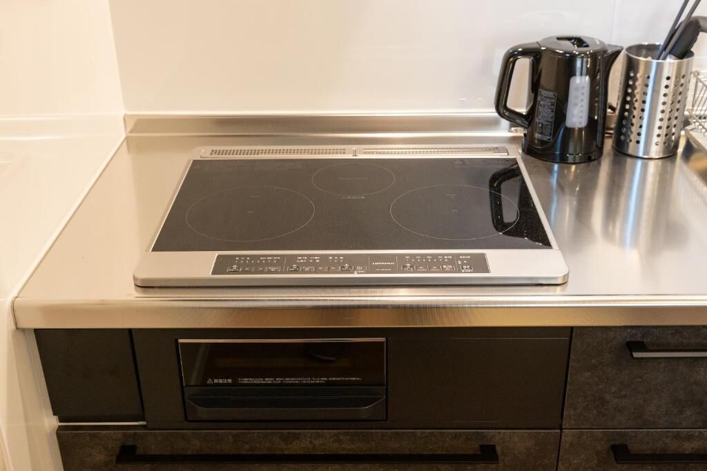 A kitchen with an induction cooktop, a built-in oven, and a coffee maker.