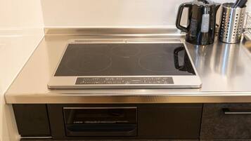 A kitchen with an induction cooktop, a built-in oven, and a coffee maker.