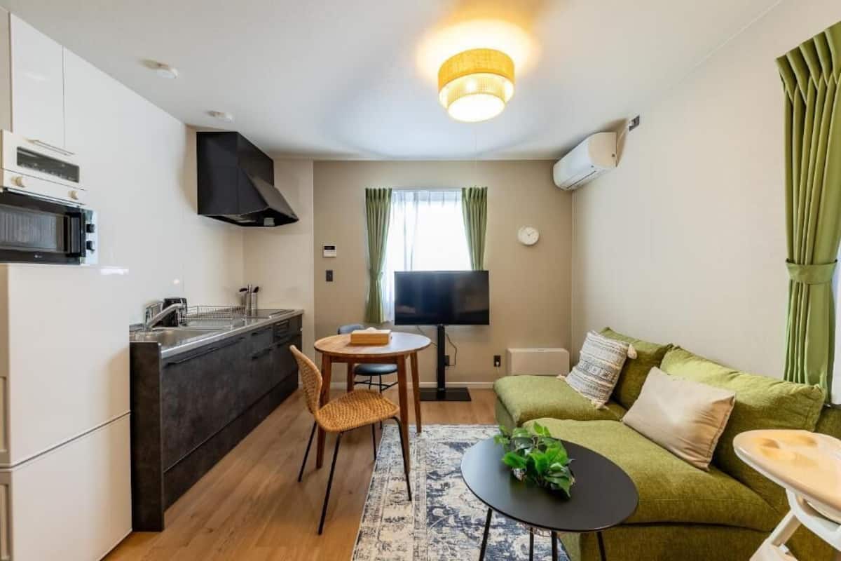 Ein gemütlicher Wohnbereich mit Küchenzeile, Essbereich, einer Couch und einem Fernseher.