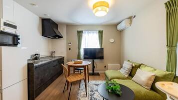 A compact living space with a kitchenette, a dining area, a sofa, and a TV.