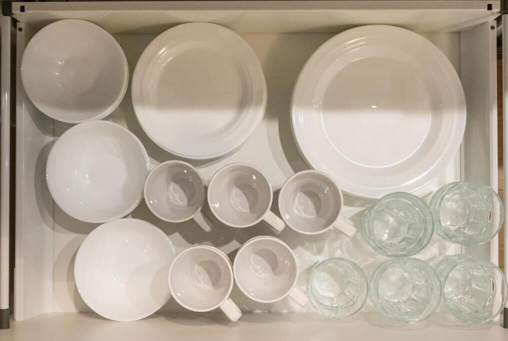 A drawer containing various white and clear glassware, including plates, bowls, and cups.