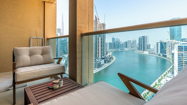 A balcony with a view of a city skyline and a river. - Lush 1BR with Canal View, 9 minutes to Dubai Mall (Dubai)
