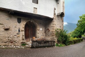 Un edificio in pietra con una porta in legno, una piccola finestra e un muro in pietra.