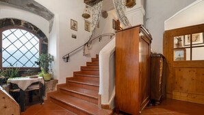 A staircase with a wooden handrail, a wooden door with glass panels, and a view through a window with a diamond pattern. - Apartment 'Helmsdorf Ritterturm' with Mountain View, Shared Garden and Wi-Fi (Lana)