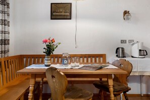 Un tavolo da pranzo in legno con sedie, un vaso con fiori, un quadro incorniciato e una macchina per il caffè su un tavolo.