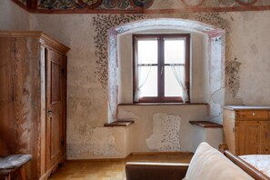 Una stanza con un armadio in legno, una panca, una finestra con vista e un piccolo ripiano.