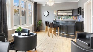 A modern kitchen with a bar area, wooden flooring, and a large window with curtains. - HernöRum - Fiskekroken (Harnosand)