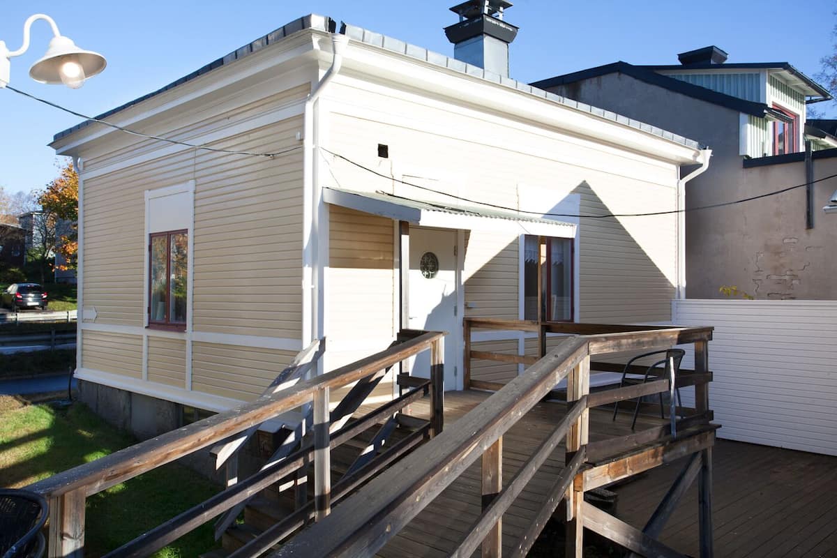 A small, single-story building with a wooden deck and a staircase leading to the entrance.