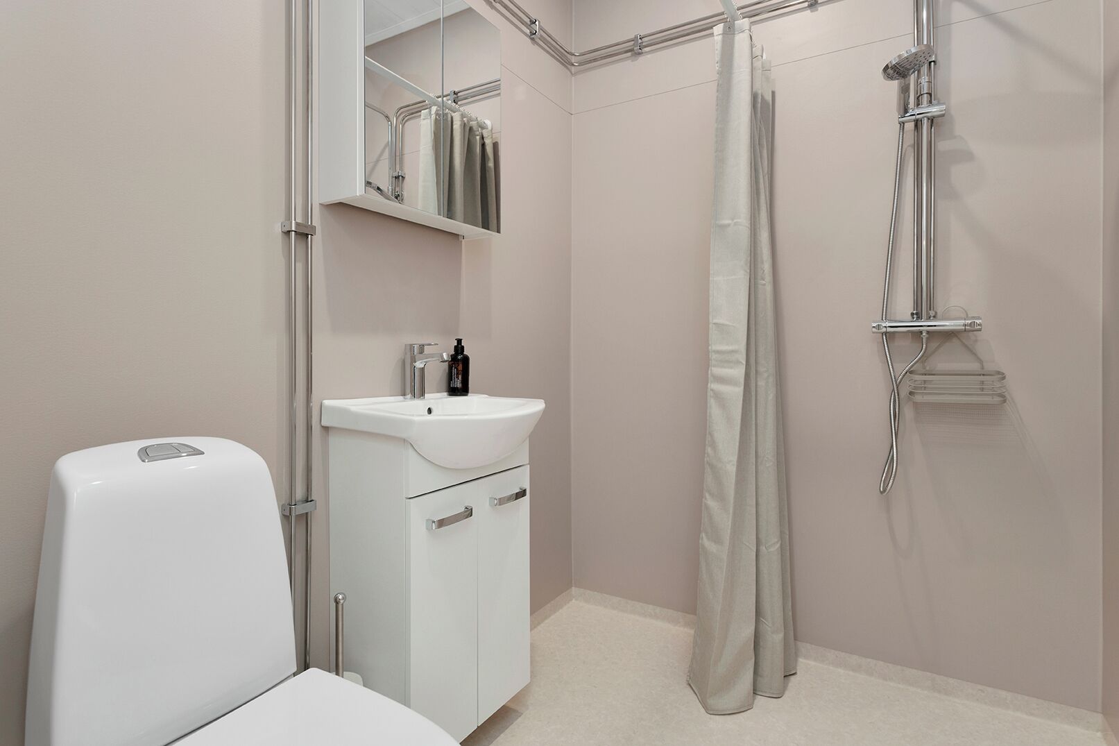Een badkamer met toilet, wastafel, spiegel, douche en een handdoekhouder.
