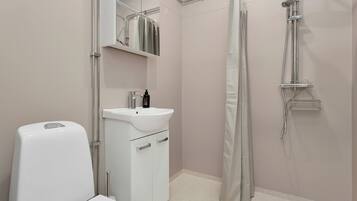 Een badkamer met toilet, wastafel, spiegel, douche en een handdoekhouder.