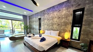 A modern bedroom with a large bed, a view of the outdoors, and a concrete accent wall.