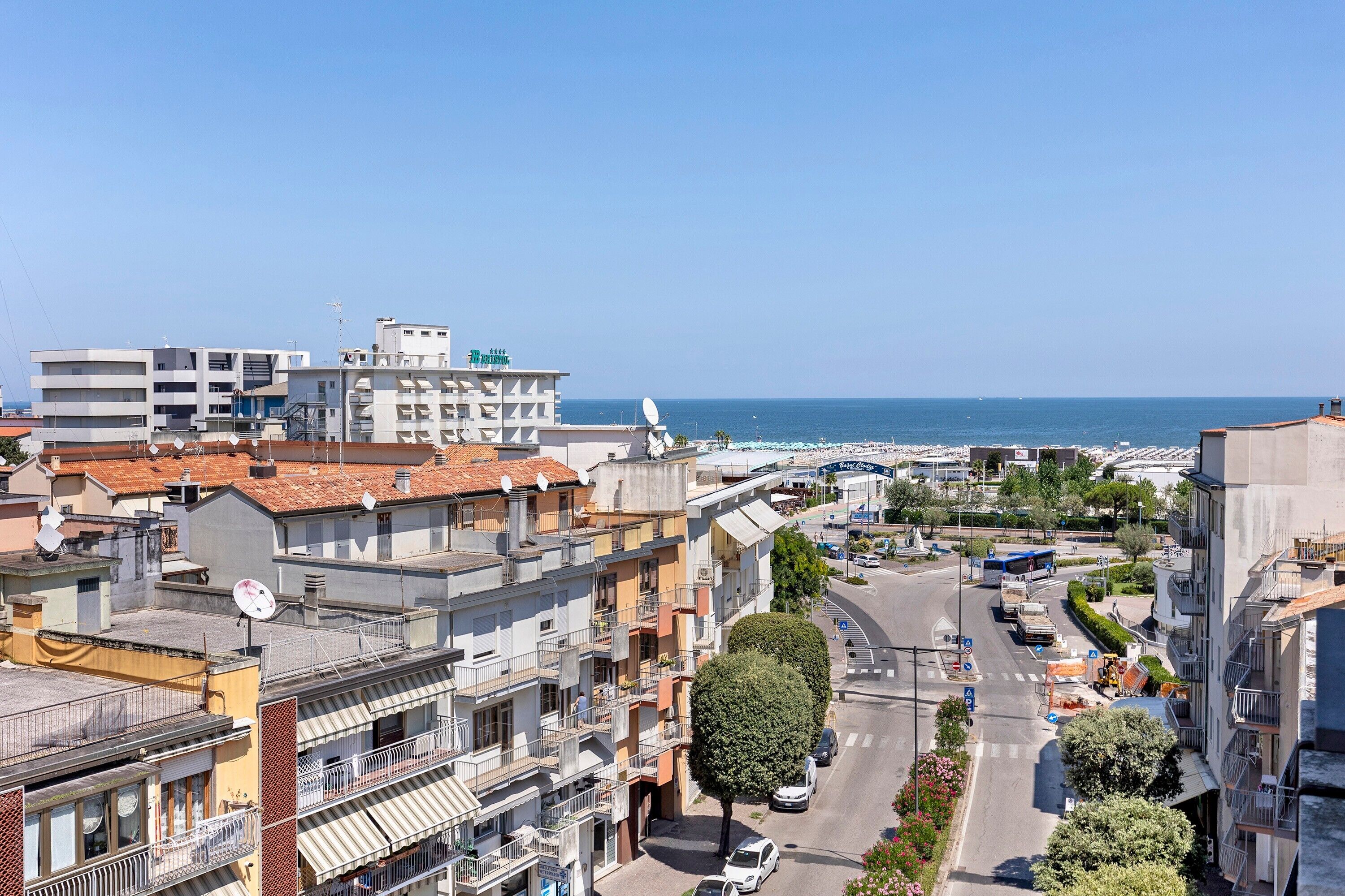 Un paysage urbain côtier avec des bâtiments, un ciel dégagé et une vue sur la mer.